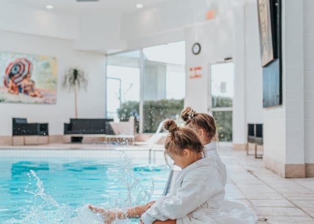 Girls sitting on pool edge in robes in Hotel Bed Inn at Laurel Point