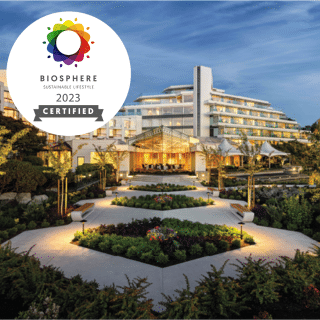 Biosphere Certified logo over image of Inn at Laurel Point at dusk